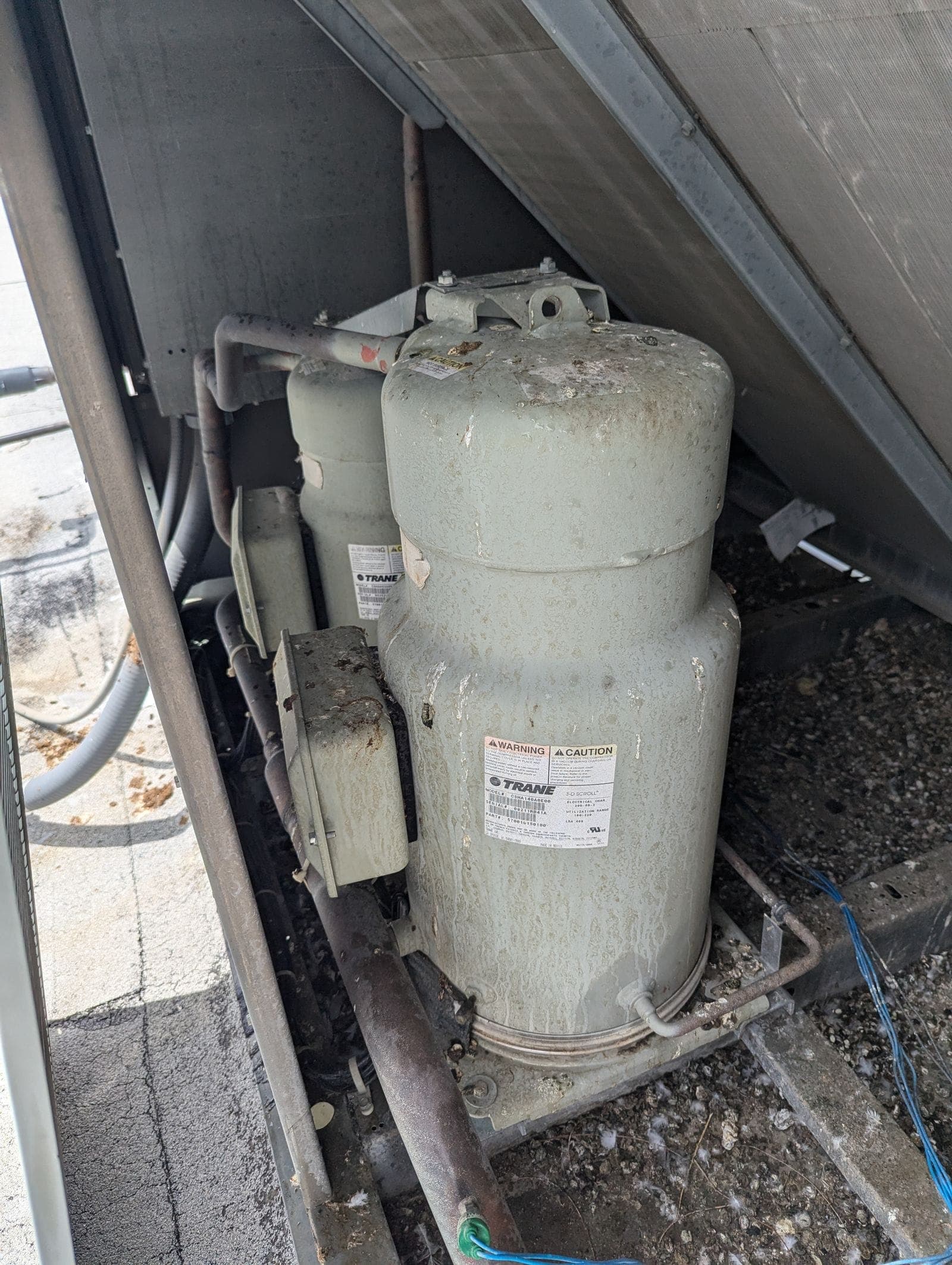 Commercial scroll compressors inside HVAC equipment being serviced