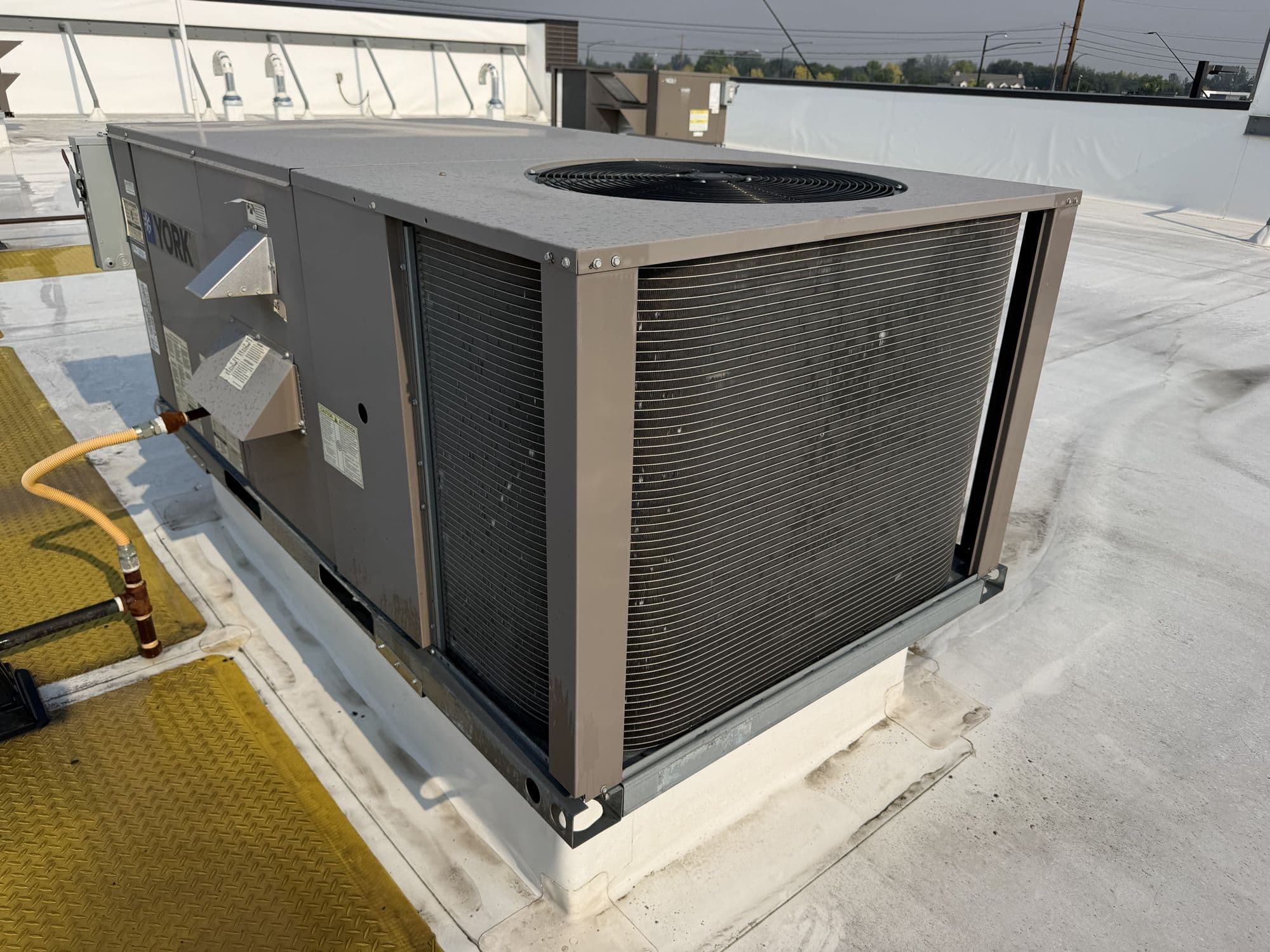 Packaged rooftop unit on a commercial roof, with its condenser coil and top-discharge fan