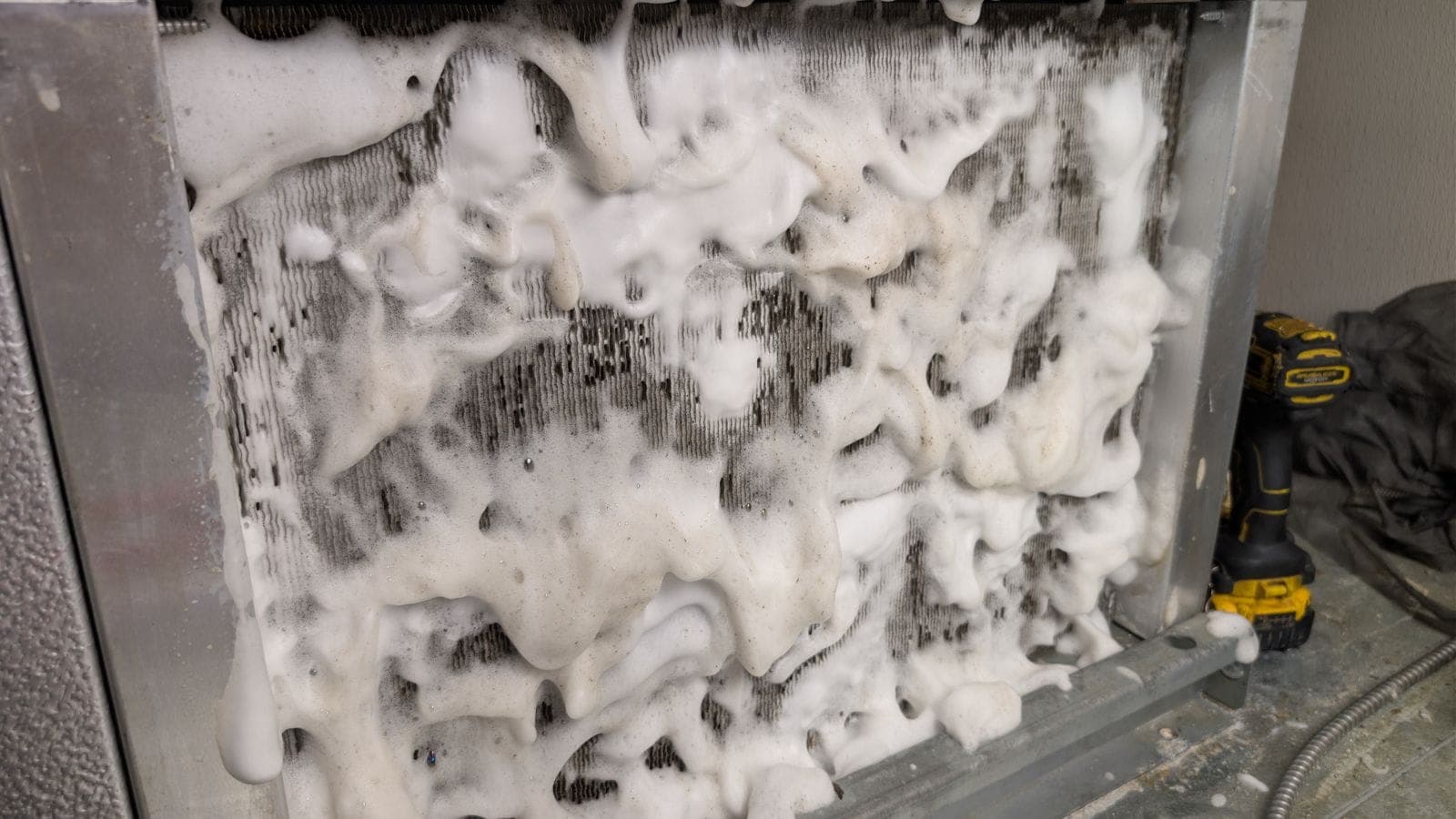 Foaming coil cleaner on a dirty condenser coil during a refrigeration maintenance visit
